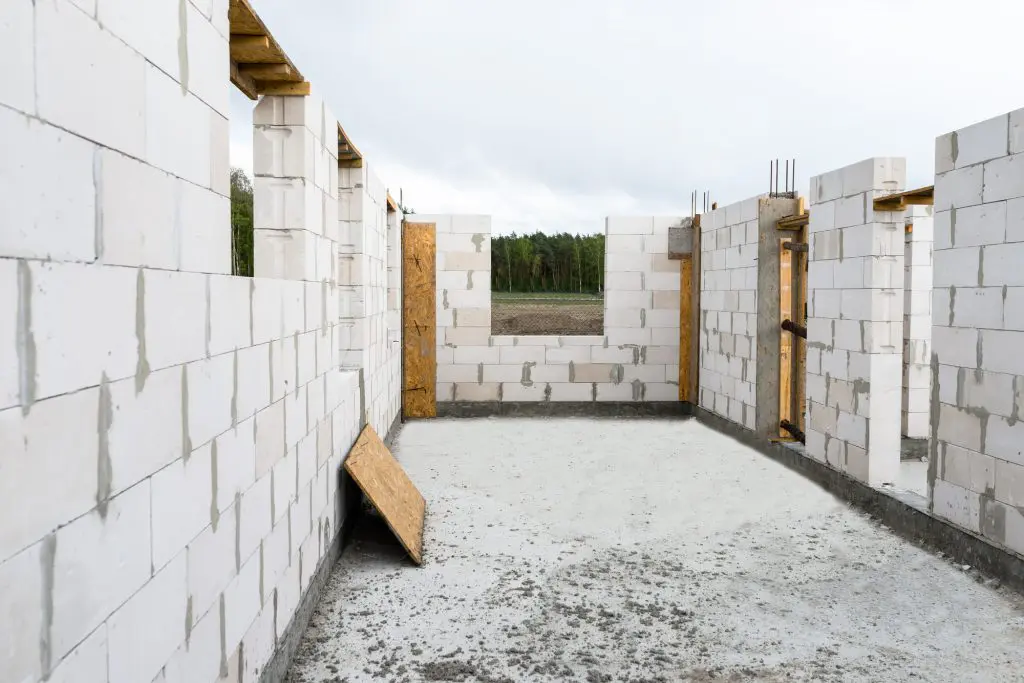 The walls of a house built of white brick with reinforced concrete pillars at the end of which there